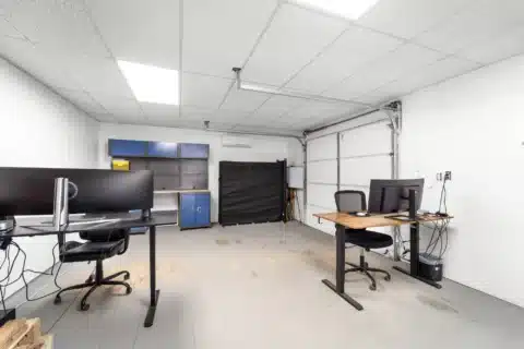 Furnished work area with desks, cabinets and an overhead garage door.