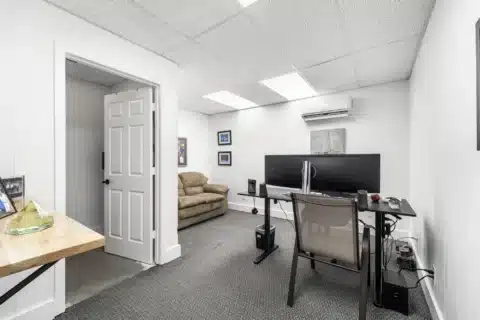 Carpeted interior office with desk, monitor and visitor seating at 706 N Main St.