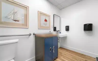 Restroom with grab bars, toilet and wall-mounted sink.