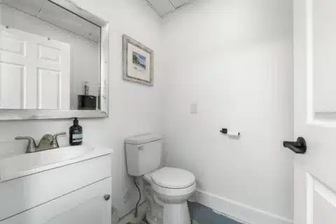 Small restroom with toilet, vanity and mirror.