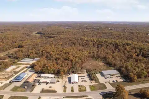 Wide aerial view of 706 N Main St and the surrounding wooded area.