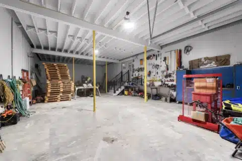 Wide workshop view with tool storage, workbenches and support columns.