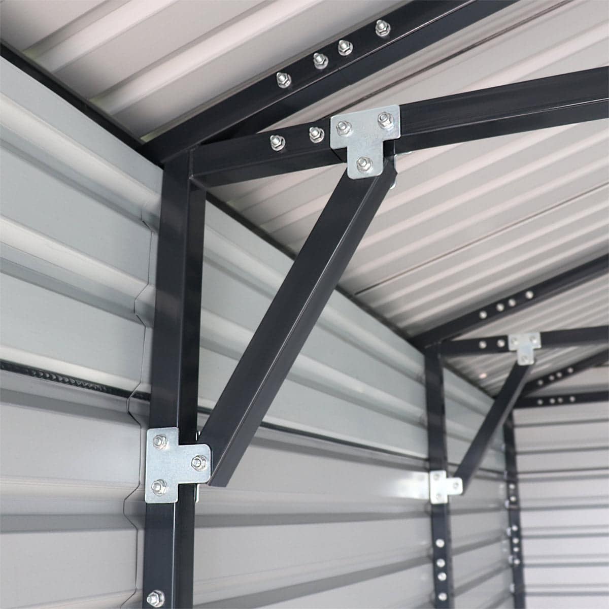 Close-up of a dark gray metal storage rack frame with bolted brackets and diagonal brace inside a metal building.