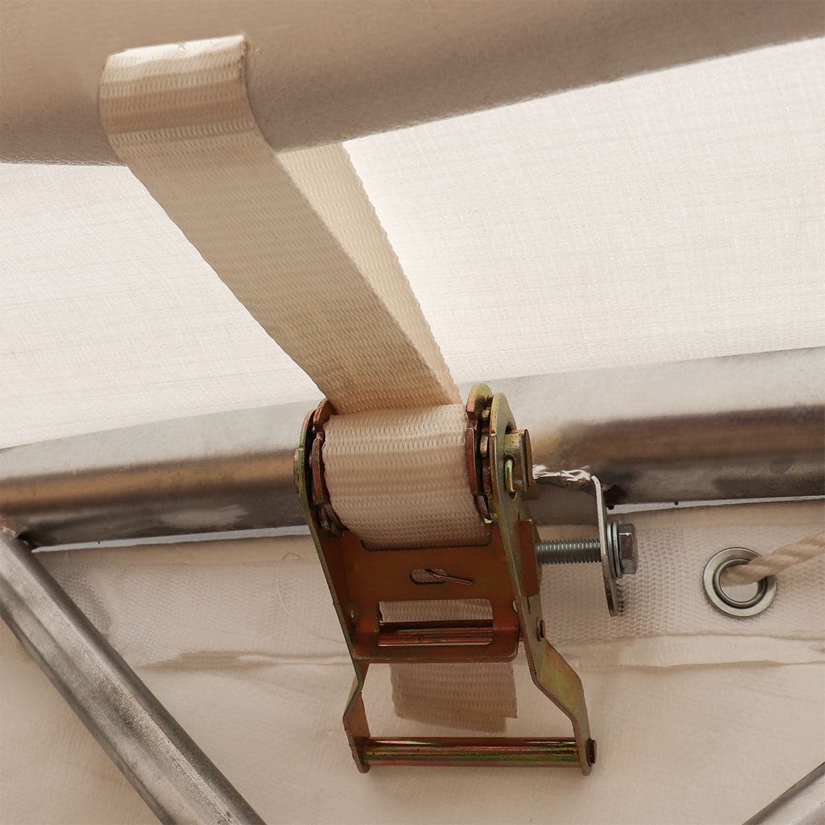 Close-up of a beige fabric strap wound around a metal roller and pulley hardware.